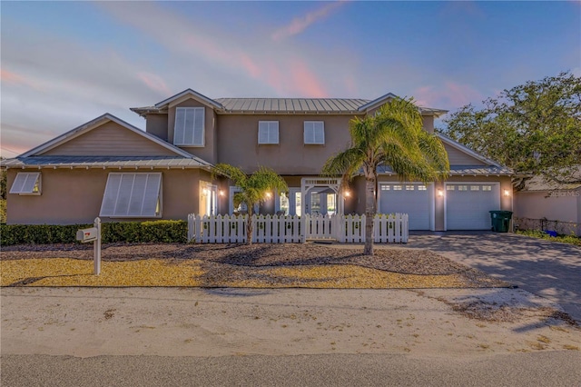201 S Cooper St, New Smyrna Beach, FL 32169 - traditional-style home featuring a fenced front yard, driveway, an attached garage, metal roof, and stucco siding