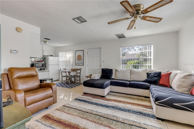 living room with ceiling fan, a textured ceiling, and light tile patterned floors