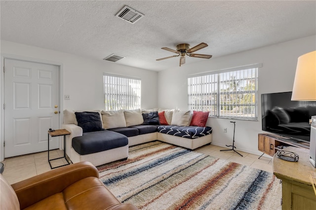 living room featuring light tile patterned flooring, a healthy amount of sunlight, a textured ceiling, and ceiling fan