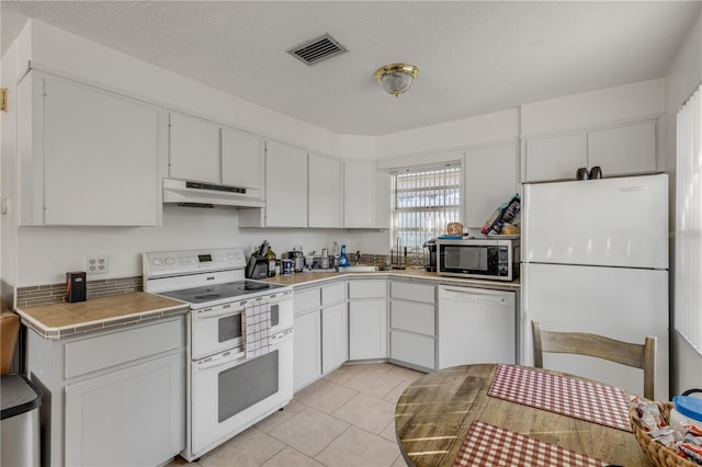 kitchen featuring white cabinetry, tile countertops, and white appliances