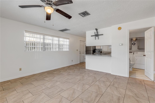 unfurnished living room with ceiling fan, washer and clothes dryer, and a textured ceiling