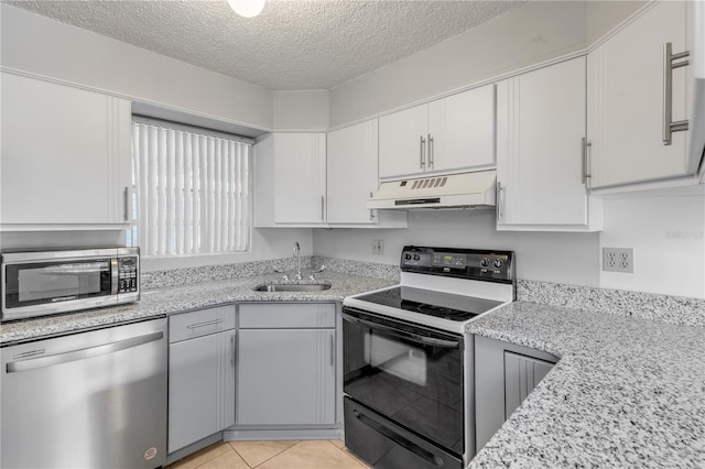 kitchen with light tile patterned flooring, sink, a textured ceiling, stainless steel appliances, and white cabinets