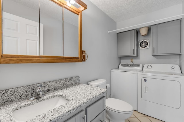 bathroom with toilet, separate washer and dryer, a textured ceiling, vanity, and tile patterned flooring