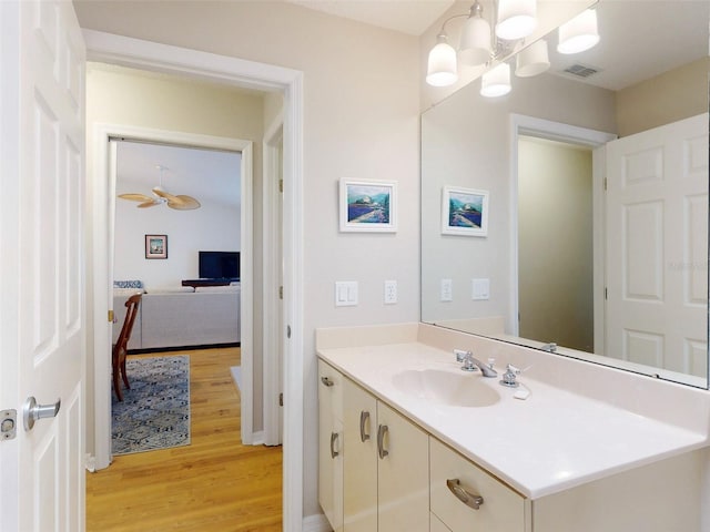 bathroom with vanity, ceiling fan with notable chandelier, and wood-type flooring