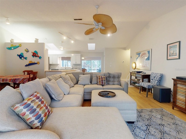 living room featuring lofted ceiling, sink, light hardwood / wood-style flooring, and ceiling fan