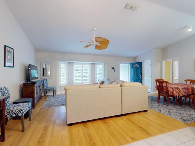 living room with ceiling fan, vaulted ceiling, and light hardwood / wood-style flooring