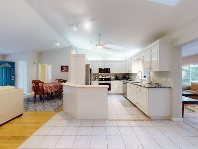 kitchen featuring light tile patterned flooring, lofted ceiling, sink, white cabinets, and stainless steel appliances