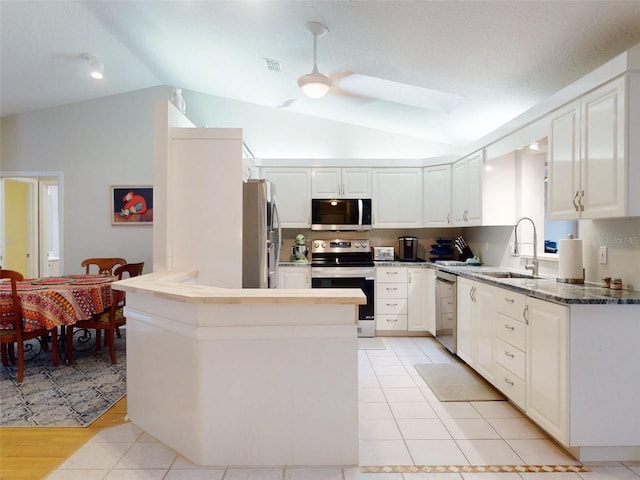 kitchen with vaulted ceiling, appliances with stainless steel finishes, white cabinetry, sink, and ceiling fan