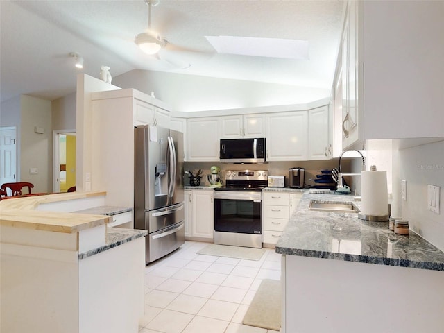 kitchen featuring lofted ceiling with skylight, sink, white cabinetry, kitchen peninsula, and stainless steel appliances