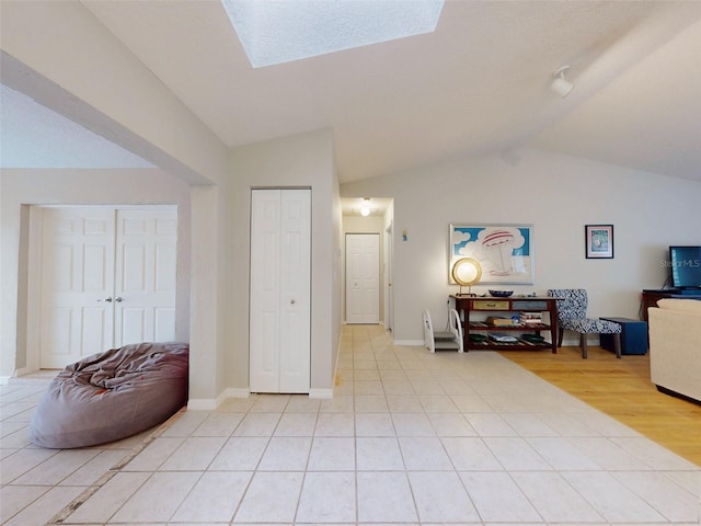 sitting room with lofted ceiling with skylight and light tile patterned flooring