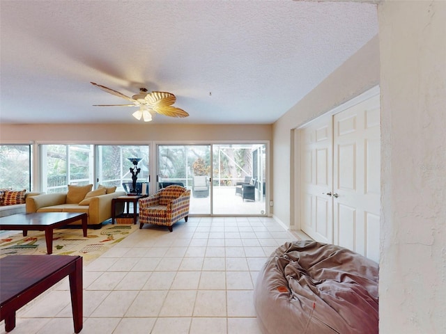 tiled living room with ceiling fan, plenty of natural light, and a textured ceiling