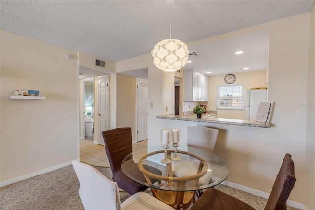 tiled dining space with a textured ceiling