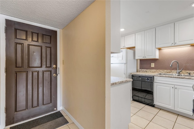 kitchen featuring dishwasher, white fridge, light tile patterned floors, and white cabinets