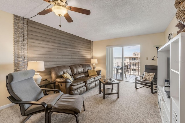 carpeted living room with ceiling fan, wooden walls, and a textured ceiling