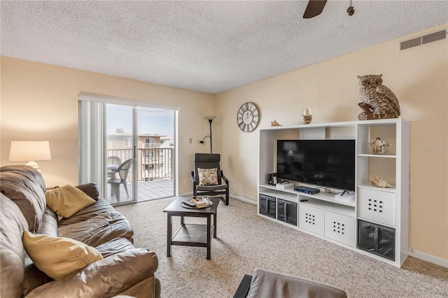 living room featuring ceiling fan, light colored carpet, and a textured ceiling