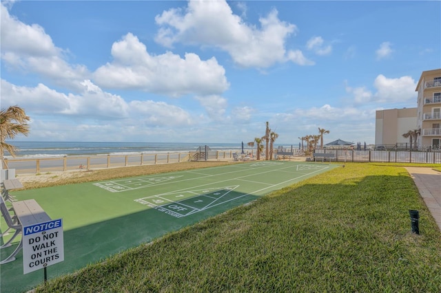 view of home's community with a water view, a view of the beach, and a lawn