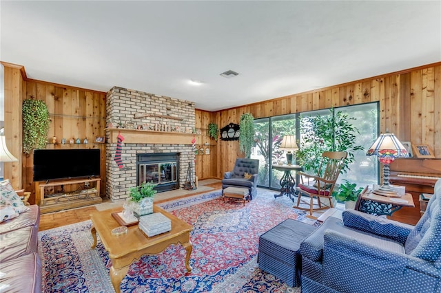 living room with crown molding, a brick fireplace, and wooden walls