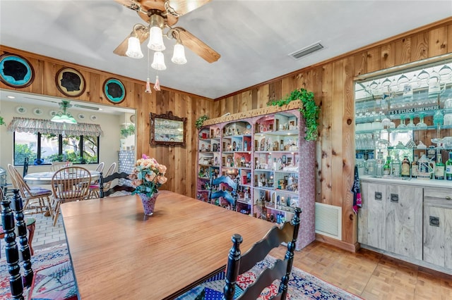 dining room with ceiling fan, light parquet flooring, and wood walls