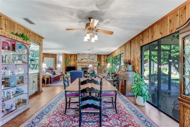 dining room with a brick fireplace, plenty of natural light, and wood walls