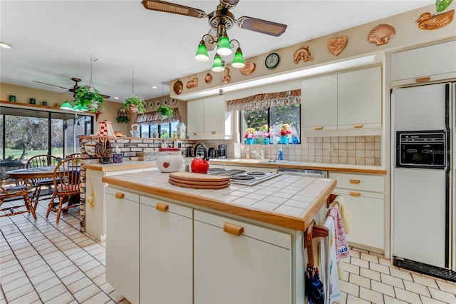 kitchen with tile counters, white cabinetry, a kitchen island, and appliances with stainless steel finishes