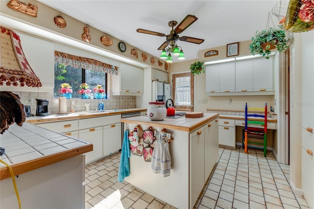 kitchen featuring ceiling fan, a center island, tile counters, white cabinets, and decorative backsplash