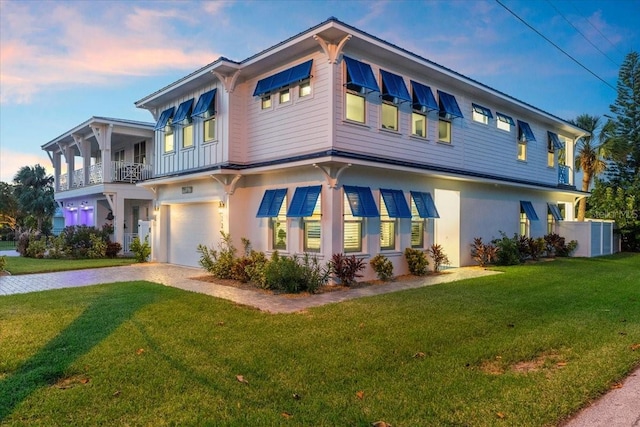 view of front of home featuring decorative driveway, a lawn, a garage, and stucco siding