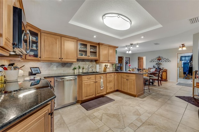 kitchen with appliances with stainless steel finishes, a raised ceiling, sink, and kitchen peninsula