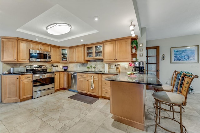 kitchen featuring a raised ceiling, appliances with stainless steel finishes, sink, and kitchen peninsula