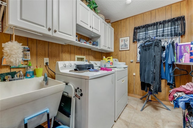 laundry area featuring sink, wooden walls, cabinets, independent washer and dryer, and a textured ceiling