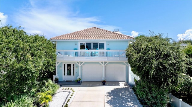 mediterranean / spanish-style house with driveway, a tile roof, and a garage