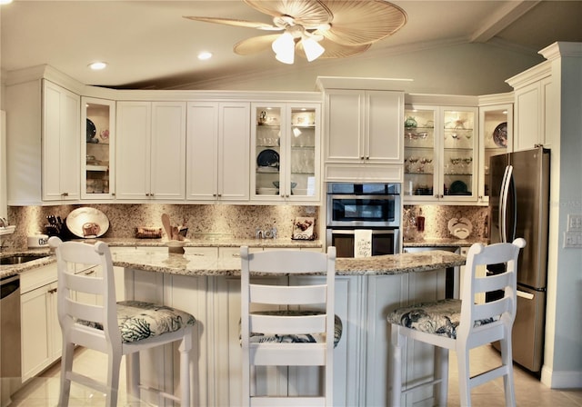 kitchen featuring stainless steel appliances, light stone countertops, a breakfast bar area, and vaulted ceiling with beams