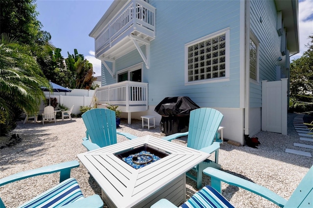 view of patio with grilling area, a balcony, and an outdoor fire pit