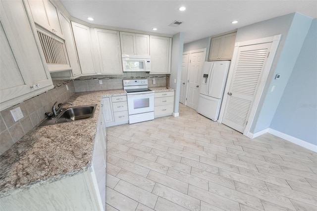 kitchen featuring sink, tasteful backsplash, light stone counters, white appliances, and light hardwood / wood-style floors