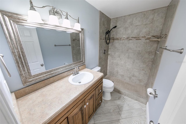 bathroom with tiled shower, vanity, and toilet