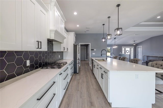 kitchen featuring a kitchen bar, sink, hanging light fixtures, stainless steel appliances, and white cabinets