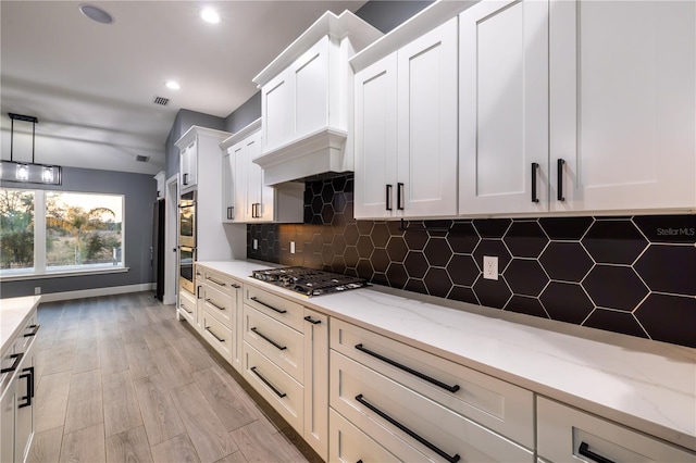 kitchen featuring pendant lighting, light stone counters, white cabinetry, and appliances with stainless steel finishes