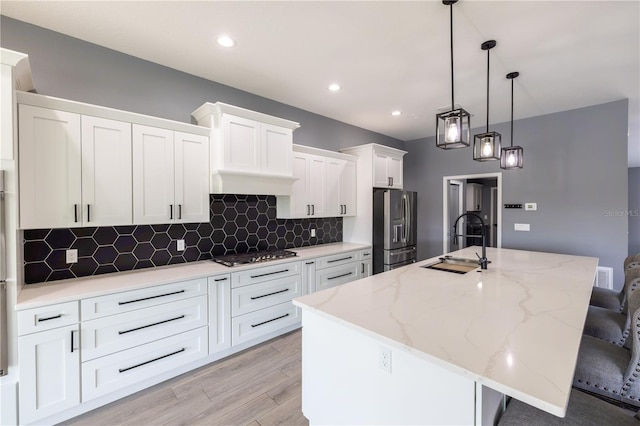 kitchen with sink, decorative light fixtures, a center island with sink, appliances with stainless steel finishes, and white cabinets