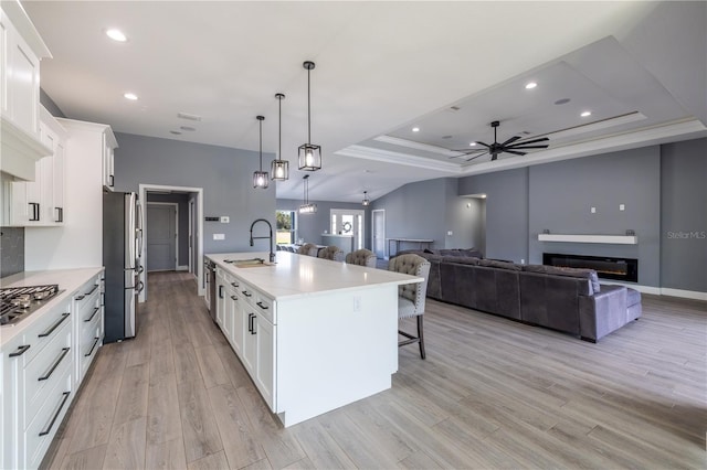 kitchen with stainless steel appliances, sink, an island with sink, and white cabinets