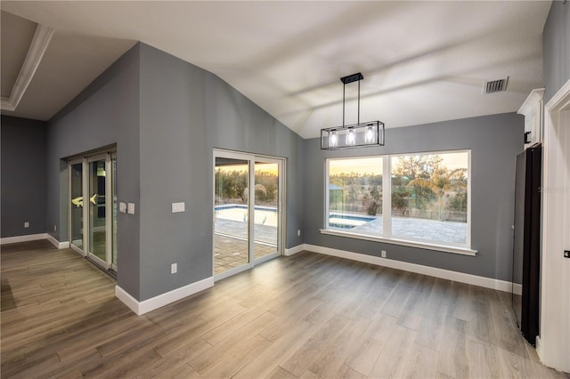 unfurnished dining area featuring wood-type flooring and vaulted ceiling