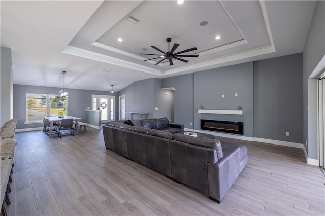 living room with ornamental molding, light hardwood / wood-style flooring, and a tray ceiling