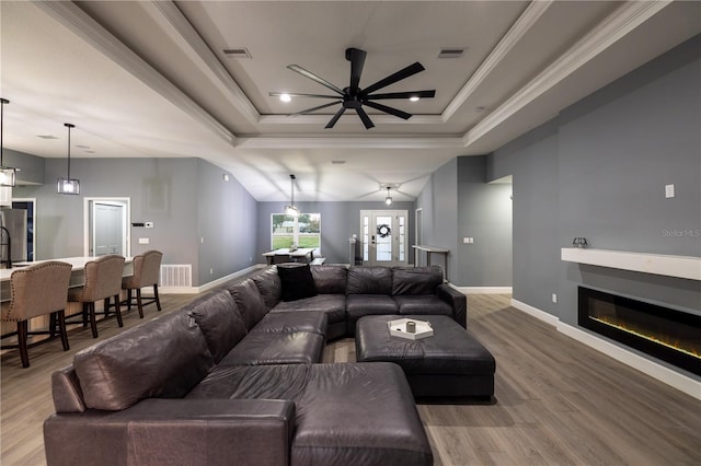 living room featuring crown molding, wood-type flooring, and a raised ceiling