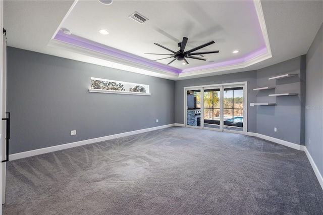 unfurnished room featuring ceiling fan, ornamental molding, a tray ceiling, and carpet flooring