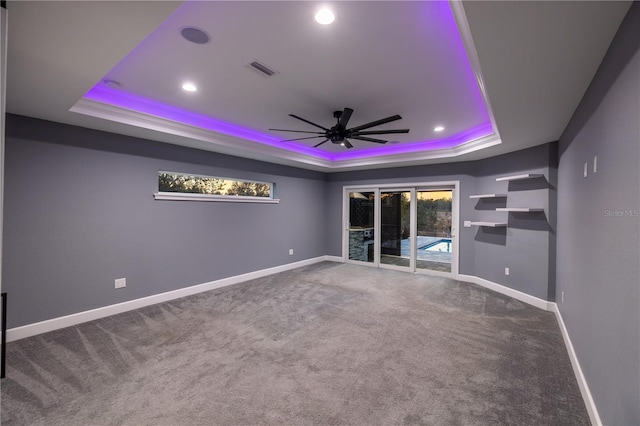 spare room featuring a tray ceiling, carpet floors, and ceiling fan