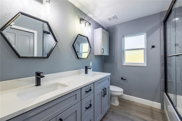 full bathroom featuring shower / bath combination with glass door, vanity, toilet, and wood-type flooring