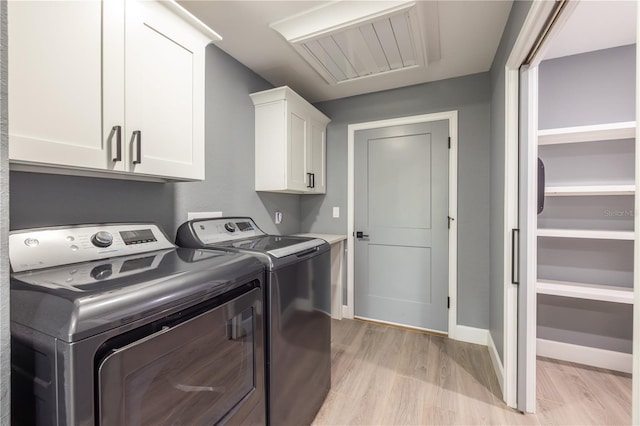 laundry area with separate washer and dryer, light hardwood / wood-style flooring, and cabinets