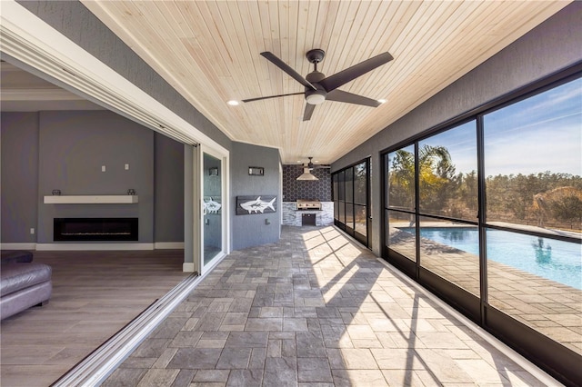 unfurnished sunroom featuring ceiling fan and wooden ceiling