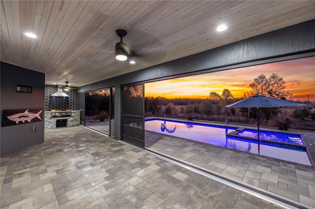 patio terrace at dusk with ceiling fan and exterior kitchen