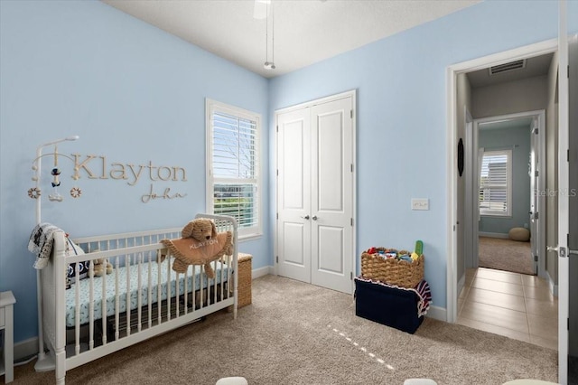 carpeted bedroom featuring a nursery area, a closet, and multiple windows