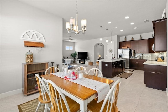 dining area featuring ceiling fan with notable chandelier, sink, and light tile patterned floors