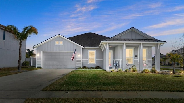 view of front facade with a garage, covered porch, and a lawn